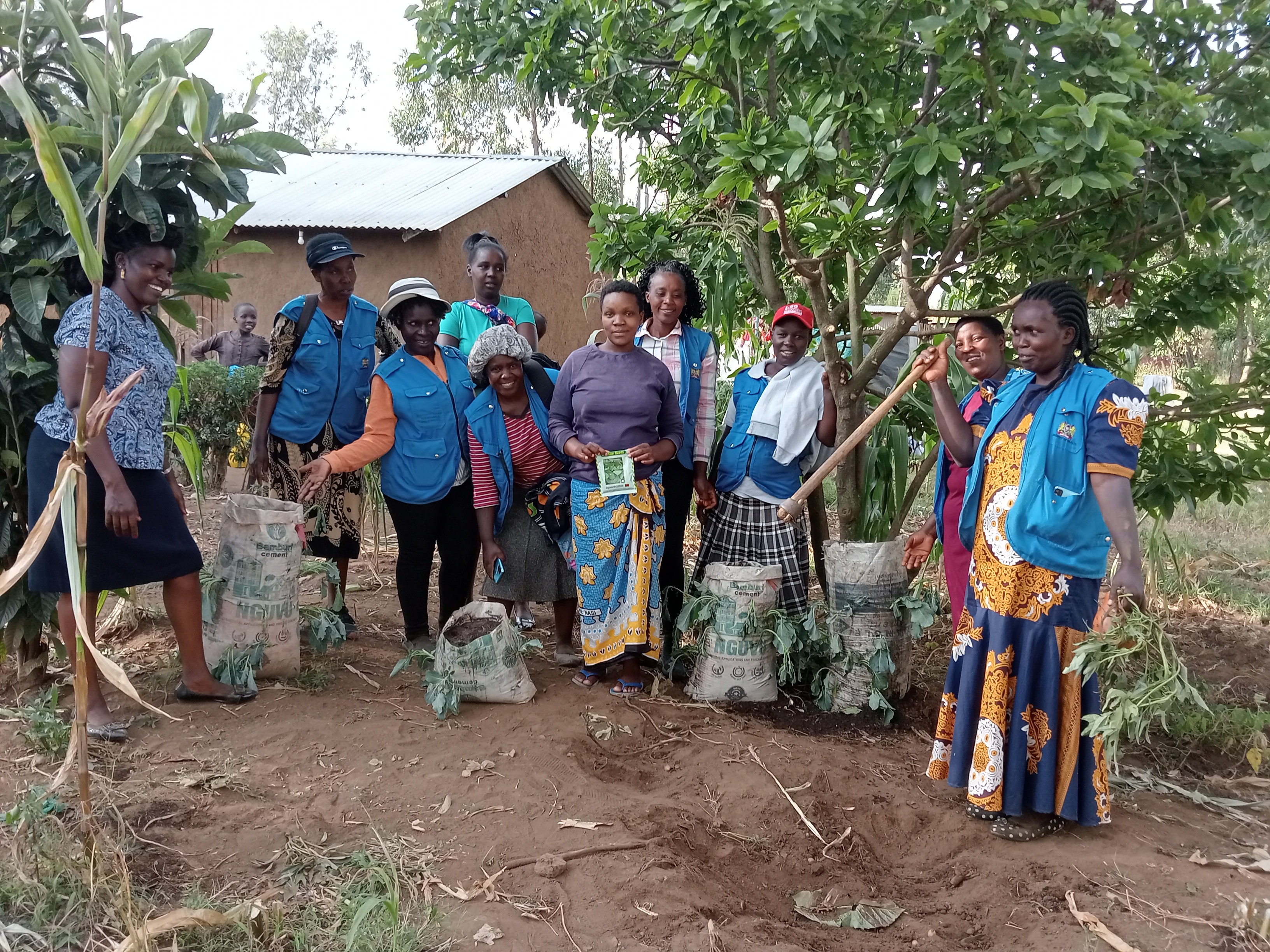 A proud beneficiary showcases her thriving managu crop, grown in recycled cement bags with support from CHPs 